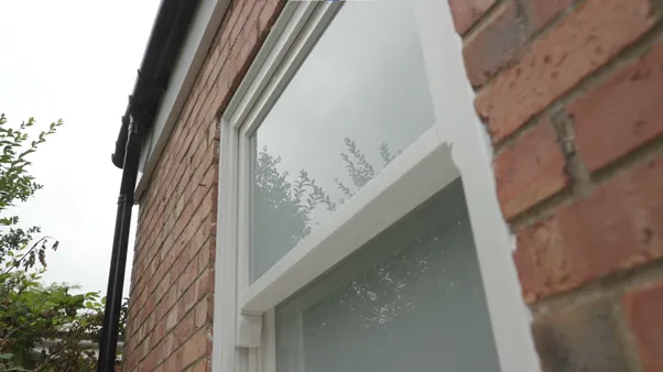 One of the new double-glazed timber sash windows seen from outside against the brick