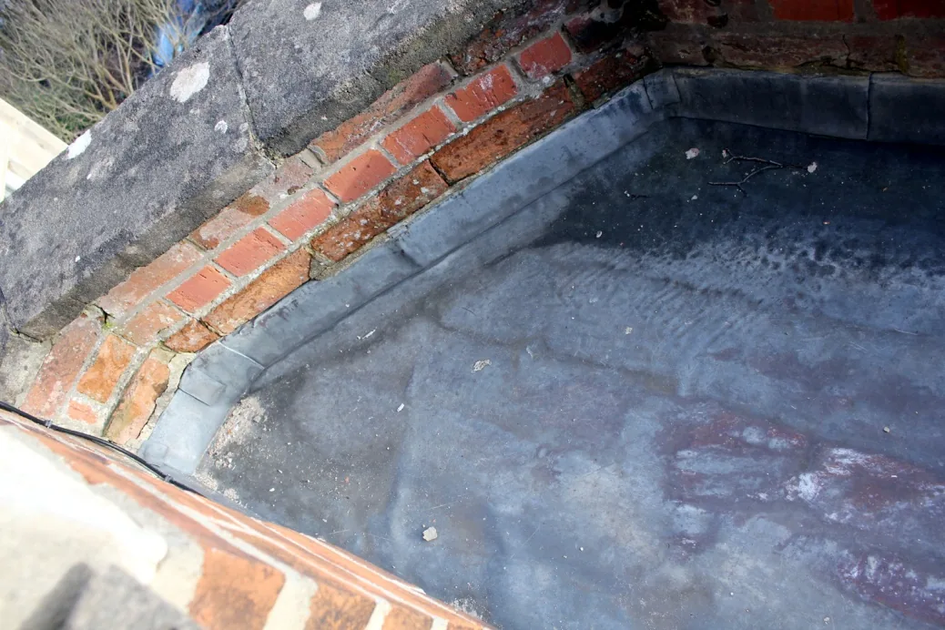 The lead flat roof over the front bay behind its brick parapet