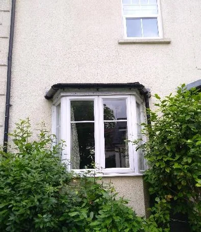 Existing 1996 uPVC double glazing in the rendered wall before replacement