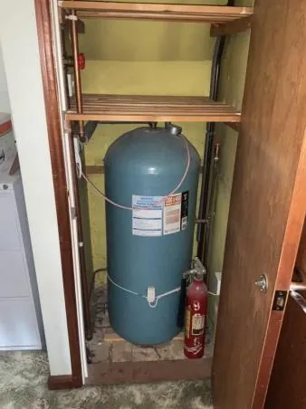 Old hot water cylinder in an airing cupboard before replacement