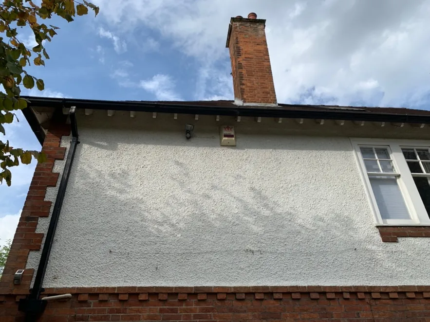 Brick chimney and gable above the roughcast rendered upper storey at Church Way
